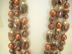 "Vintage triple strand necklace made in Hong Kong. 16\", 18\", & 20\" strands of brown, bronze, & gold tone beads. Large oval beads have gold tone caps. Hook fastener. Excellent condition." Brown Multi-strand Beaded Necklaces, Vintage Brown Multi-strand Beaded Necklaces, Vintage Brown Multi-strand Beaded Necklace, Brown Gold Beads Multi-strand Necklace, Brown Multi-strand Beaded Necklace With Gold Beads, Evening Necklace, Funky Necklace, Glass Bead Necklace, Plastic Beads