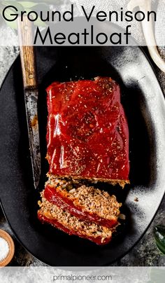 meatloaf on a black plate with text that reads ground venison meatloaf