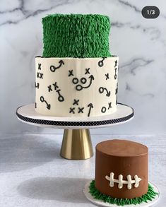 two cakes decorated with grass and footballs on top of each cake stand, one is white