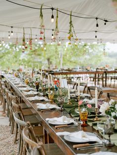 a long table is set up with place settings and candles for an outdoor wedding reception