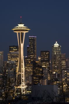 the space needle is lit up at night in front of the cityscape and skyscrapers