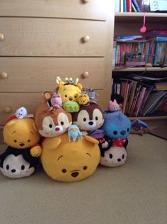 a group of stuffed animals sitting on top of a bed next to a book shelf