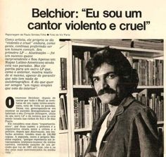 a man with a moustache standing in front of a book shelf filled with books