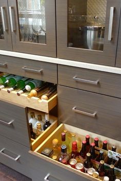 an open drawer in a kitchen filled with bottles