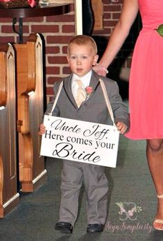 a little boy in a suit and tie holding a sign that says uncle jeff here comes your bride