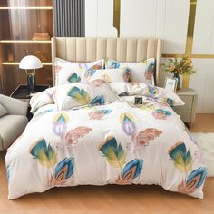 a bed with colorful feathers on it in a room next to a chair and lamp