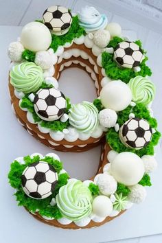 a cake shaped like the number eight with soccer balls and grass around it on a table