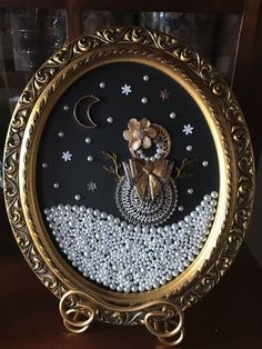 a gold frame with beaded artwork on it's sides and a moon in the background