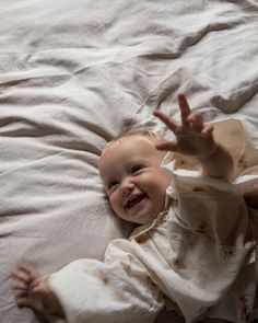 a smiling baby laying on top of a bed