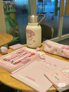 a wooden table topped with lots of pink items and writing utensils on top of it