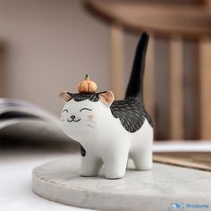 a ceramic cat figurine with a black and white cat on top of it's head