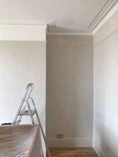 an empty room with a ladder in the corner and paint on the wall behind it