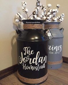 two black jars with cotton flowers in them