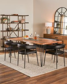 a dining room table with four chairs and a wine glass on the centerpiece, in front of a bookshelf