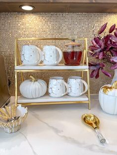 there is a shelf that has some cups and saucers on it with flowers in the background