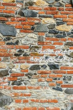 an old brick wall with a clock on it's side and some rocks in the background