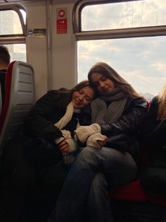 two women sitting on a bus with their arms around each other