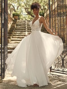 a woman in a white dress is standing on some steps and posing for the camera