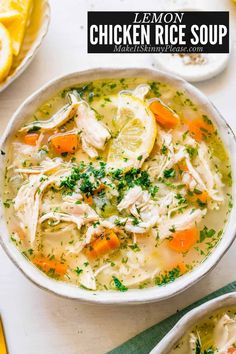 chicken rice soup in a white bowl with lemons and parsley on the side