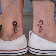 two people with matching tattoos on their feet, one is holding the other's hand