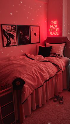 a bedroom with pink walls and pictures on the wall above the bed in front of it