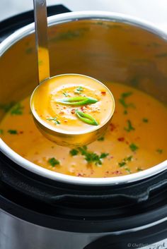 a ladle full of soup is being lifted from the slow cooker by a spoon