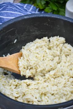 rice being cooked in a pot with a wooden spoon