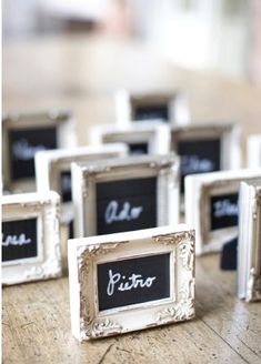 small white frames with black chalk on them sitting on a wooden table next to each other