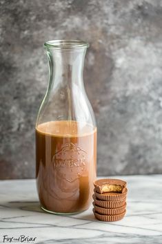 a glass carafe filled with liquid next to cookies