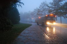 a school bus driving down the road in the rain at night with its headlights on