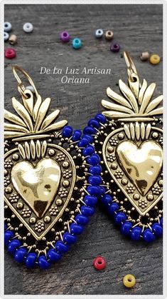 two pairs of gold and blue beaded heart shaped earrings on top of a wooden table