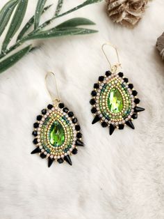 two pairs of green and black beaded earrings on top of a white furnish