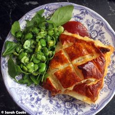 a blue and white plate topped with food next to a green leafy vegetable salad