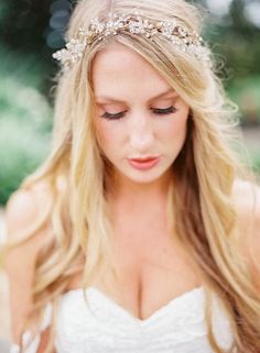 a woman with long blonde hair wearing a tiara and holding a flower in her hand