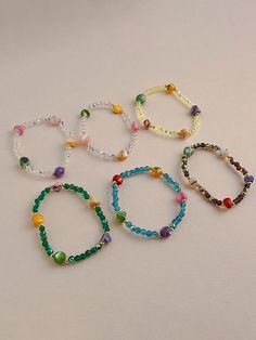 six bracelets with beads and glass beads on white table top next to small vase