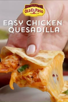 a hand holding up a piece of chicken quesadilla