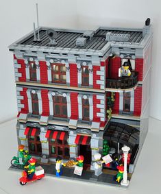 a lego model of a building with people standing in front and on the street outside