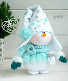 a stuffed snowman wearing a blue and white hat with pom - poms