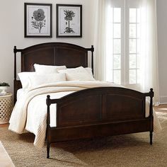 a bedroom with white walls and wooden bed frame in front of two pictures on the wall