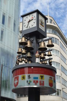 a large clock tower with bells on it's sides in front of a building