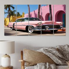 an old pink car parked in front of a pink building with palm trees on the side