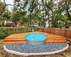 a hot tub sitting on top of a wooden deck next to a tree filled yard