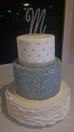 a three tiered cake with silver and white frosting