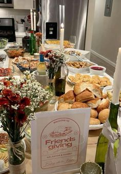 a table full of breads and wine bottles with flowers in vases on it