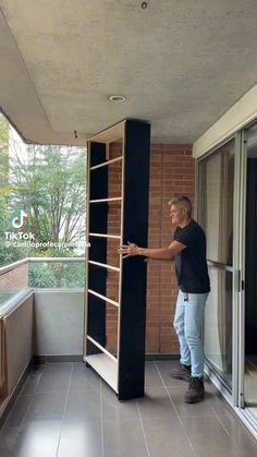 a man standing on top of a balcony next to a tall book shelf filled with books