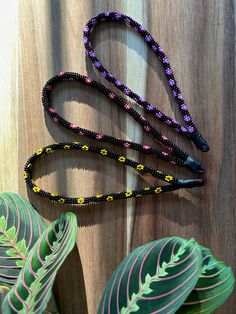 a long beaded lanyard on a wooden surface next to a leafy plant