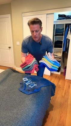 a man standing in front of a bed with clothes on it