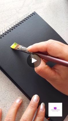 a woman is using a pair of scissors to cut out a piece of paper on top of a notebook