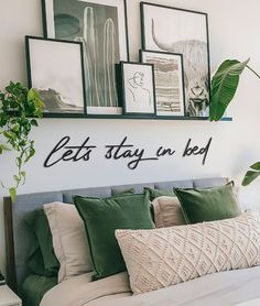 there is a bed with pillows and pictures on the wall above it that says let's stay in bed