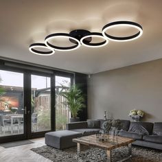 a living room with couches, tables and lights on the ceiling in it's center